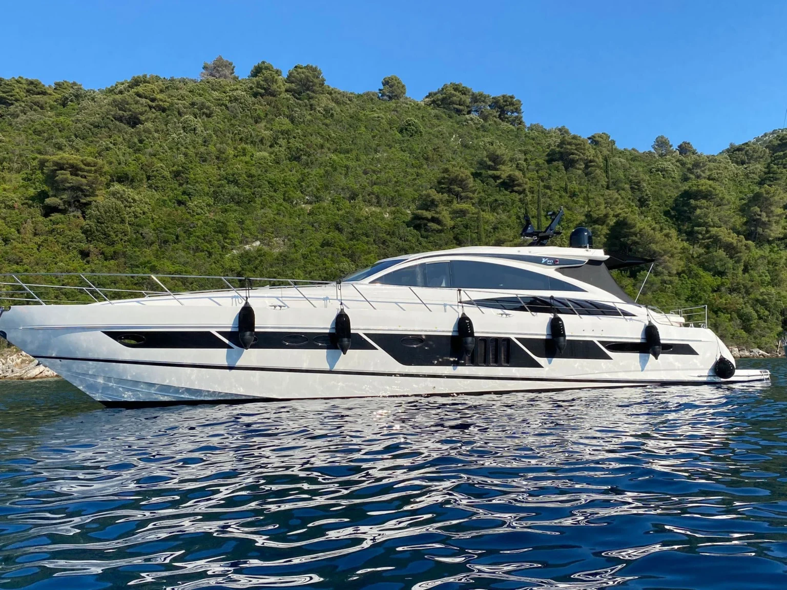 Princess V70 in profile at anchor below a wooded hillside